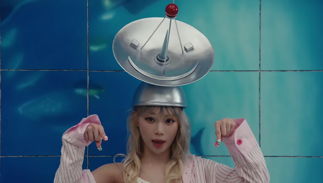 A close up shot of LE SSERAFIM's Chaewon with a satellite on her head from their CRAZY music video.